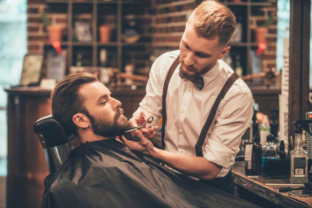 Barber/Stylist School in Maryland Barber cutting man"s beard with scissors