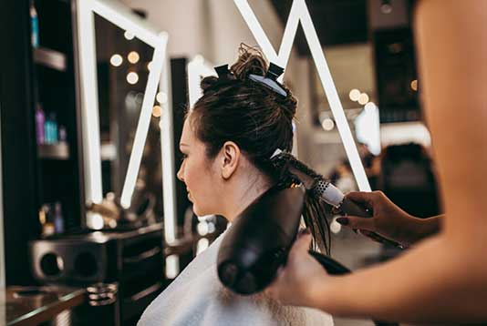 Blow Dry Stylist in Maryland using blow dryer and brush techniques on customer's hair