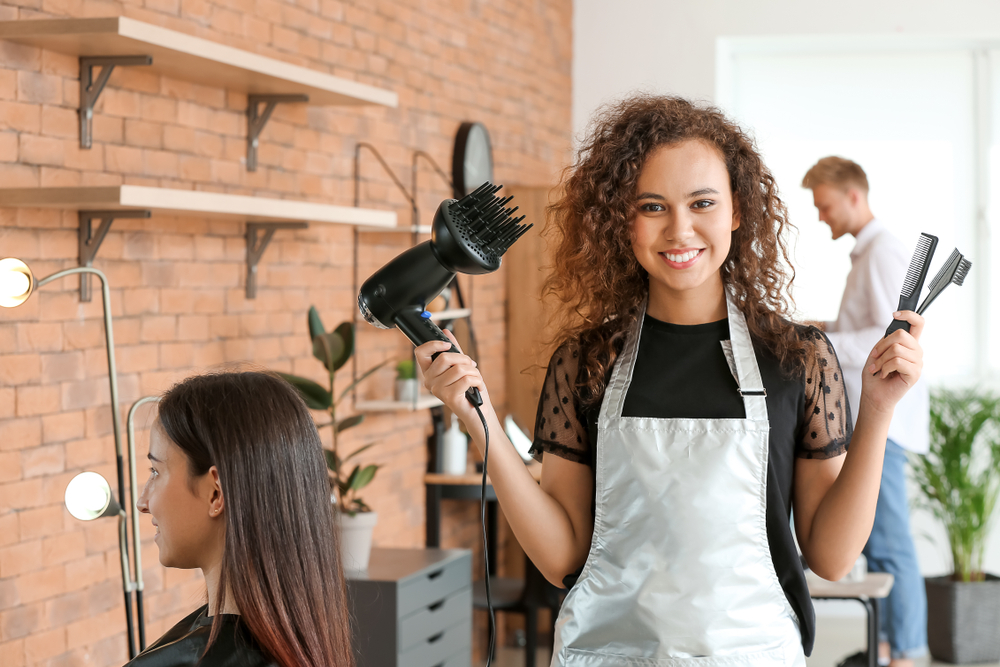 hairstylist with tools in her hand doing a client's hair